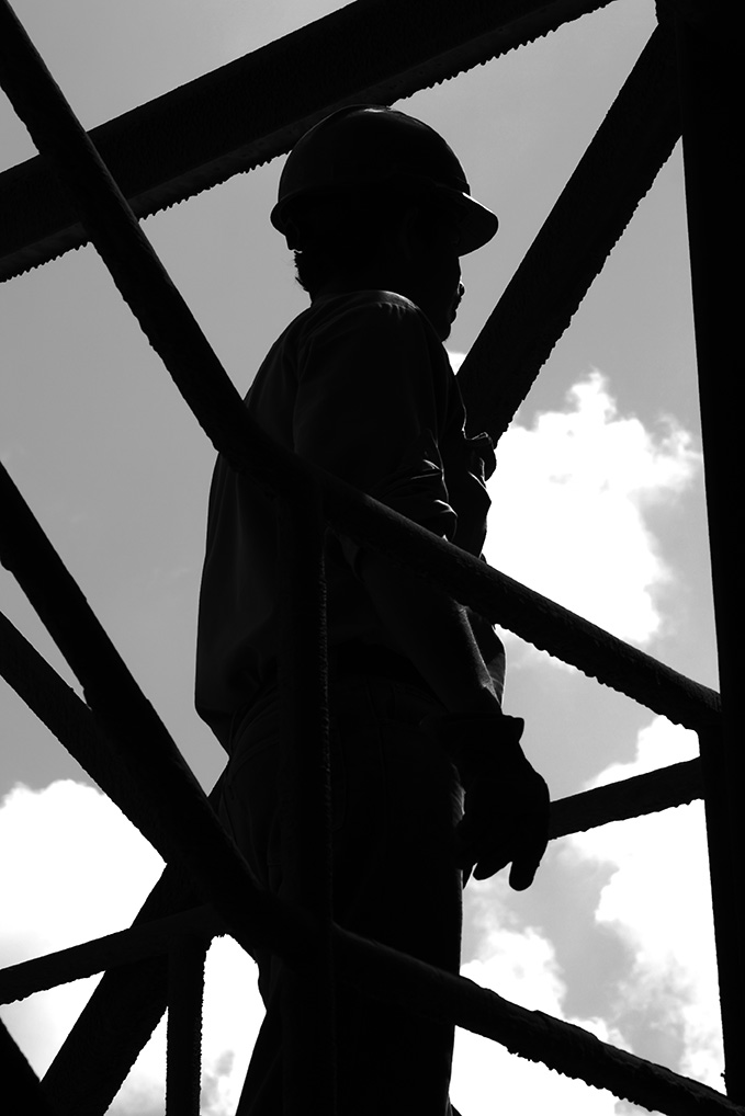 silhouette of construction worker looking out through structural beams