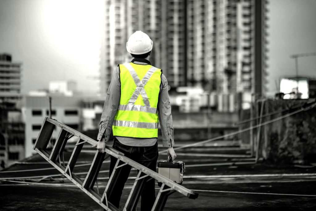 construction worker holding ladder on job site