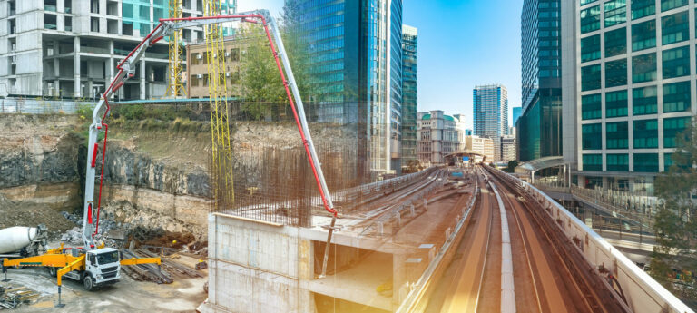 Construction works. Erection of railway line. Construction of bridge in city. Machine pours concrete during construction. Building work in metropolis. Erection of skyscraper in downtown